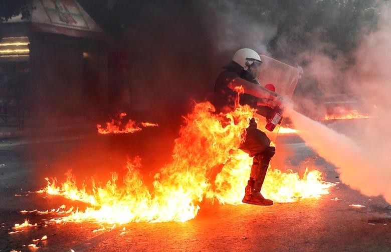 A riot police officer extinguishes a fire during a demonstration against government plans to regulate street protests, in front of the parliament building in Athens, Greece. REUTERS/Alkis Konstantinidis  